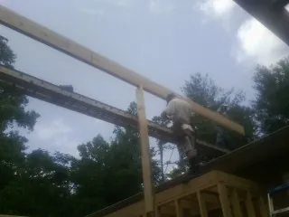 Carpenter setting a ridge beam over a new addition frame — Ice Dam Removal by Roofing Brothers in Elmsford