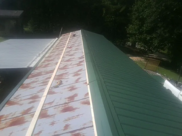 Old rusted panels beside newly installed green metal roofing — Wind Damage Roof Repair by Roofing Brothers in Elmsford