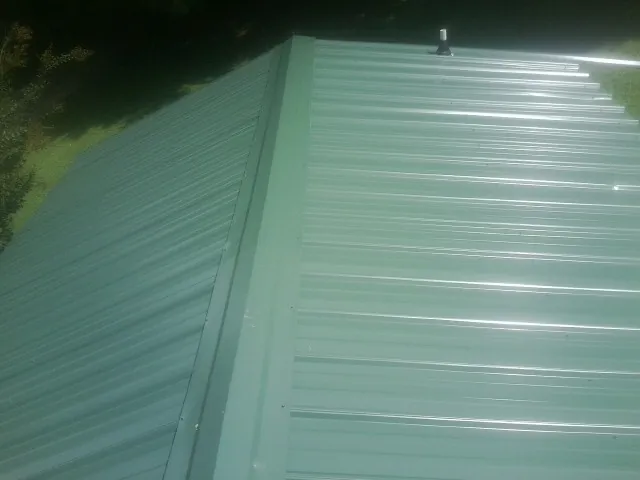 New green metal panels meeting at the ridge of a roof — Flat Roof Repair work by our crew in Elmsford
