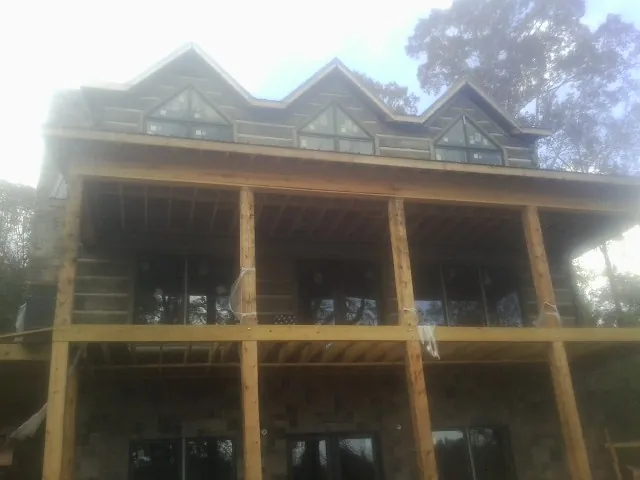 Dormers and porch framing on a large log home under construction — Roof Coating work by our crew in Elmsford