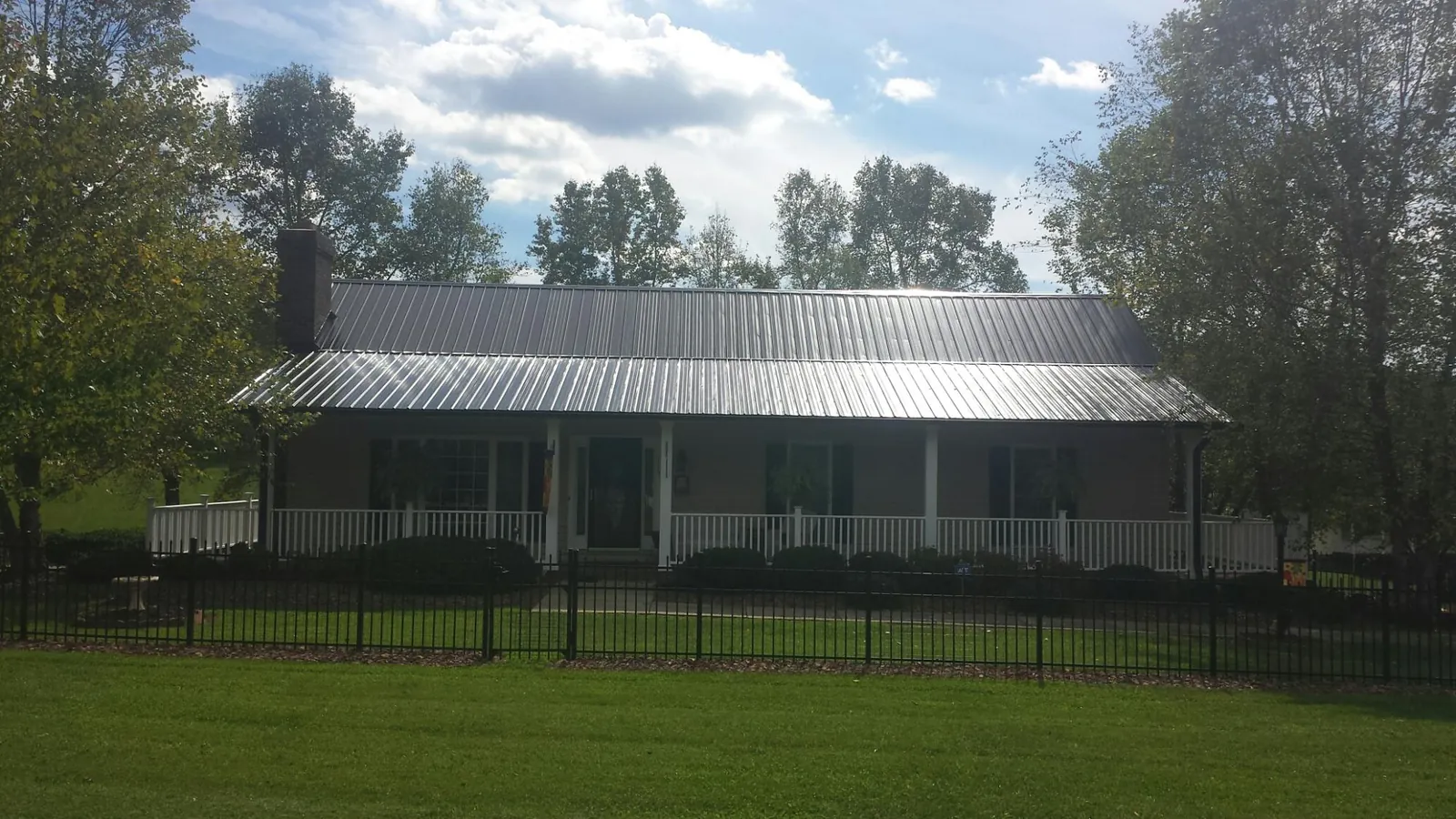 Gray metal roof on a brick ranch with a full width front porch — Gutter Guard Installation work by our crew in Elmsford