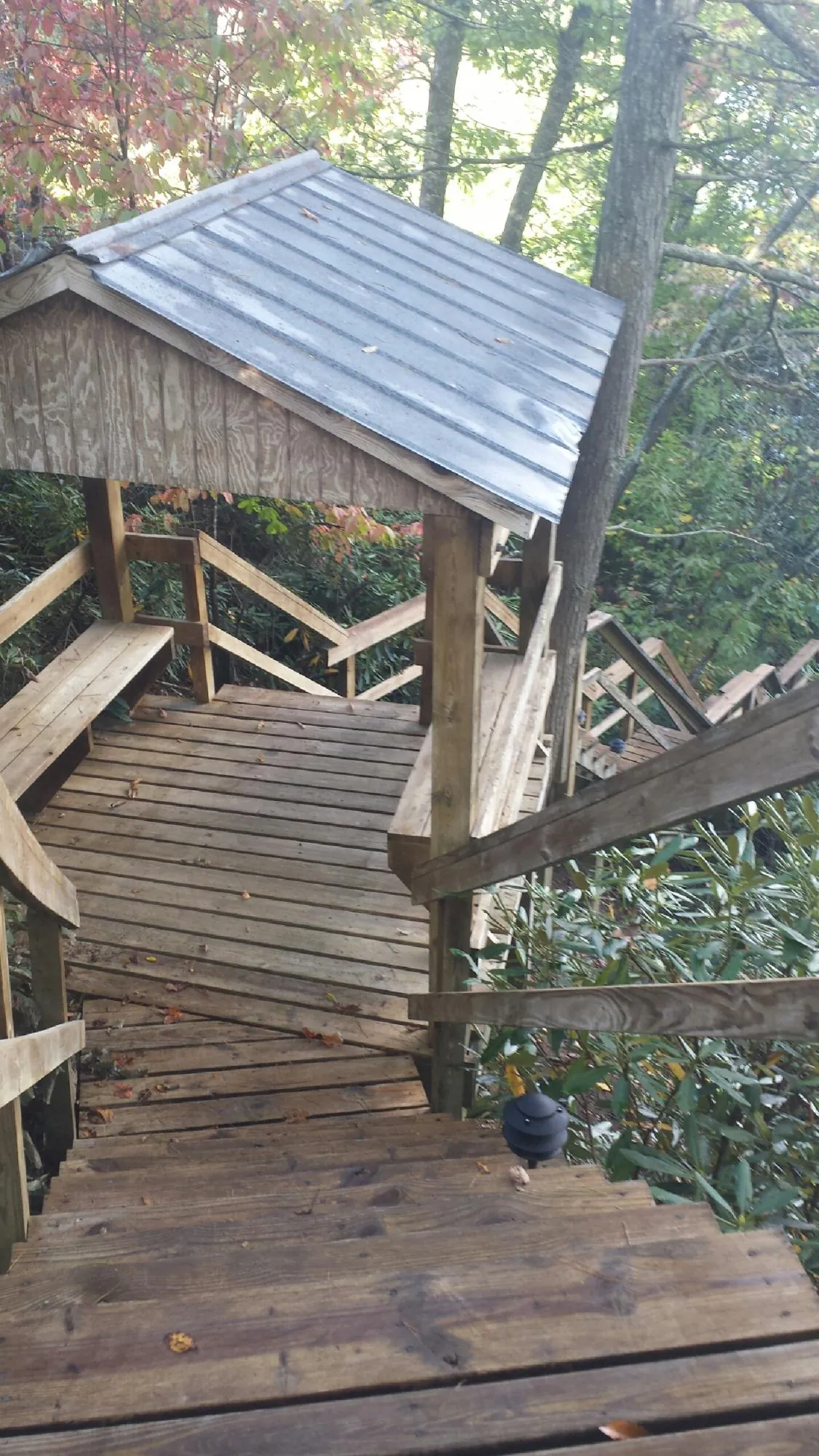 Metal roofed shelter over wooden steps on a wooded walkway — Skylight Repair & Installation work by our crew in Elmsford